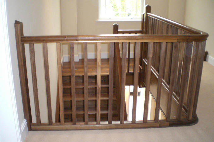 Staircase with Open Strings and Curved Bottom Treads made in American Walnut and French Polished