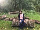 A young person sitting on a log in the park