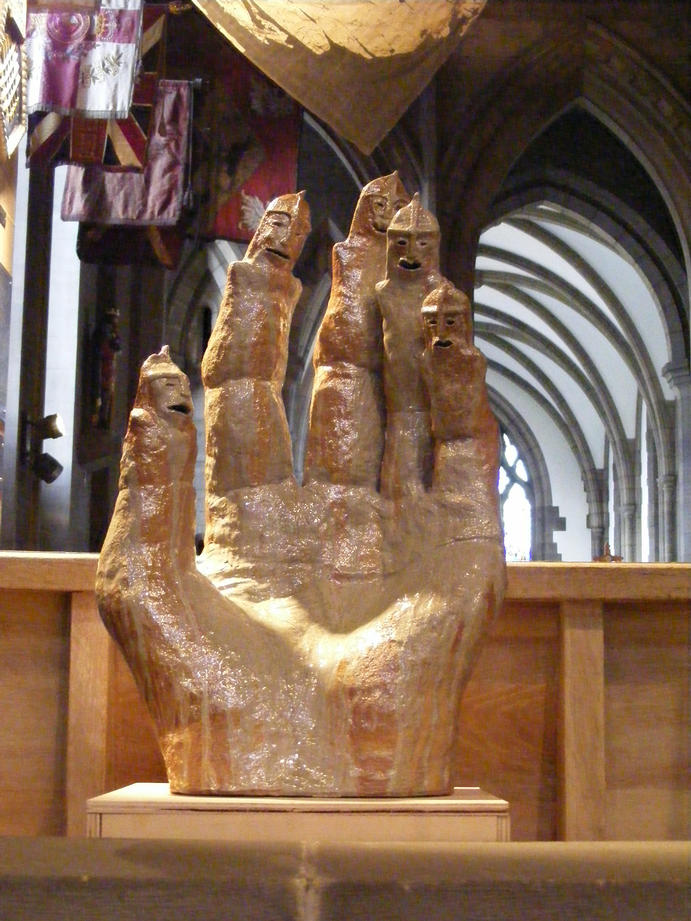 A single wood fired stoneware hand, about 80 cms tall, the fingers of which become caricatures of soldiers with helmets