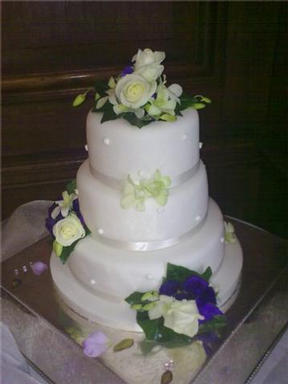 Fresh roses and orchid  clusters dressed this cake